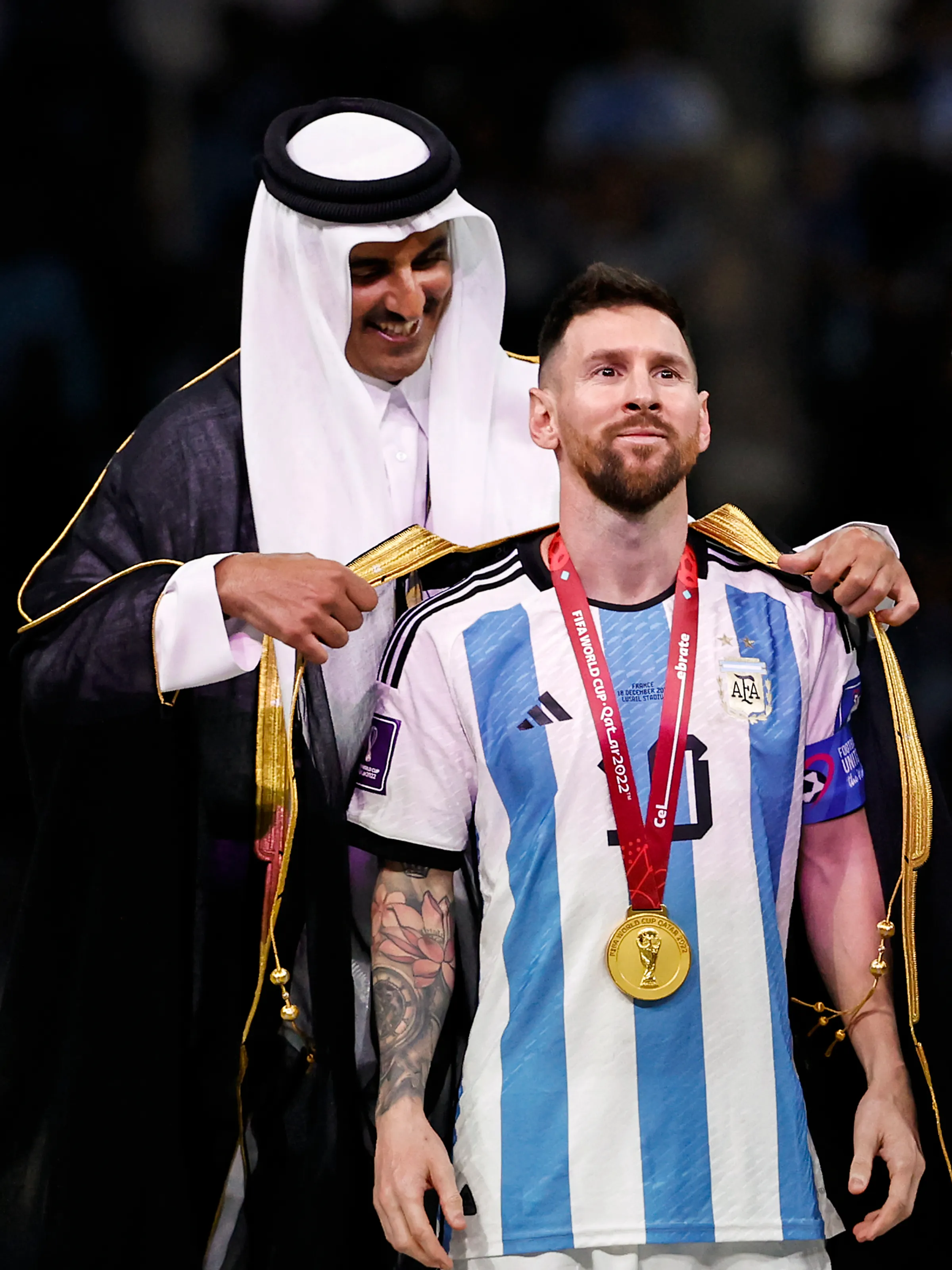 Wereldkampioen Lionel Messi krijgt een Arabische mantel omgehangen door de emir van Qatar .