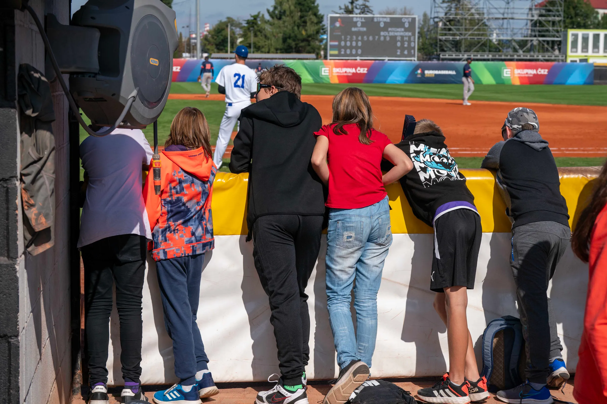 Kinderen op dd werkplek van fotografen bij het eerste honk, waar je volgens Henk Seppen ruimte moet hebben om de coach die daar staat te kunnen ontwijken en als er een actie is op het tweede honk dien je ook de eerste honkman te kunnen ontwijken. 'Dan heb je echt de (lege) ruimte in de breedte nodig om de foto te maken En dat moet in een fractie van secondes'.